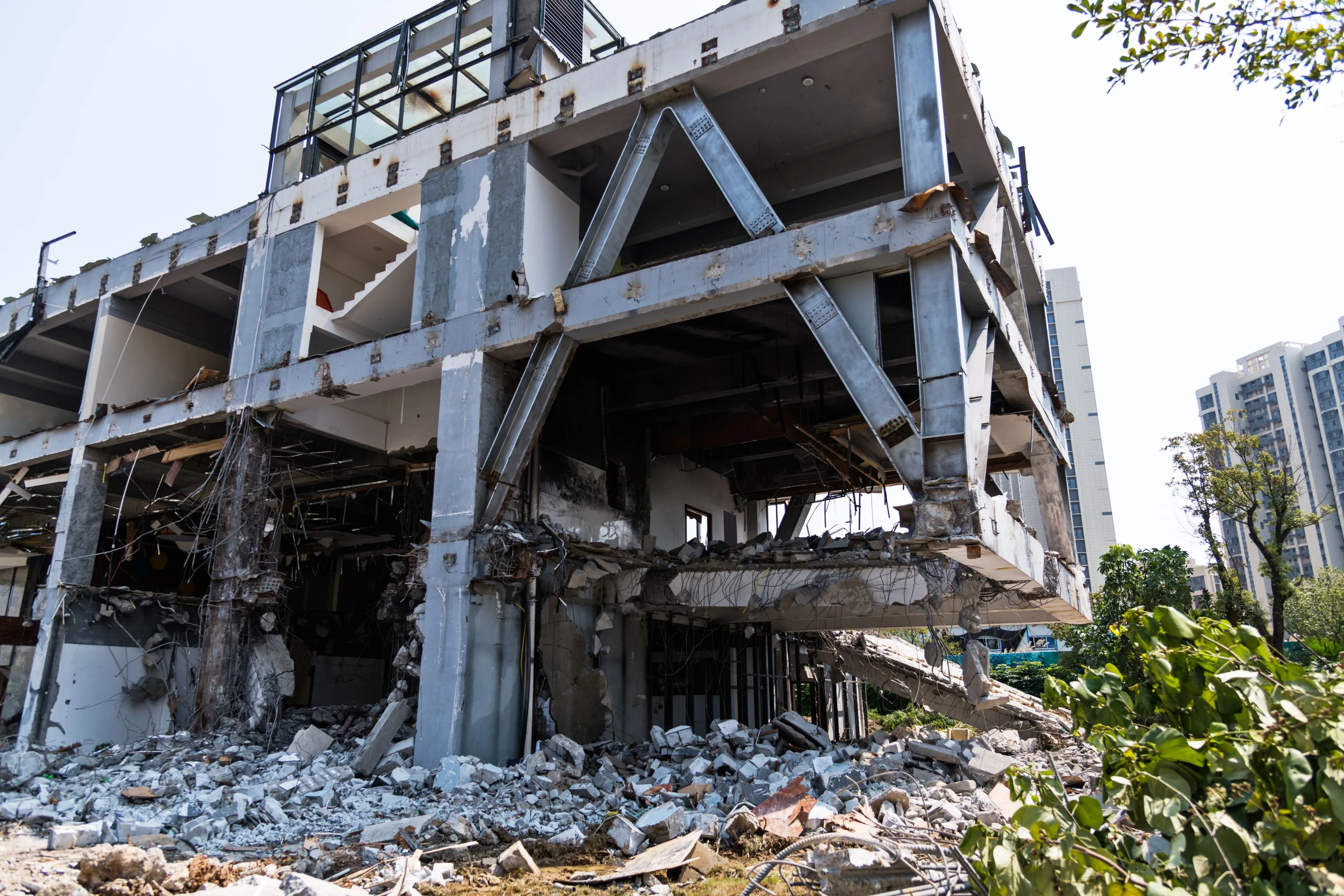 View from inside a commercial demolition site in Dallas showing a high-reach excavator breaking through reinforced concrete and rebar.